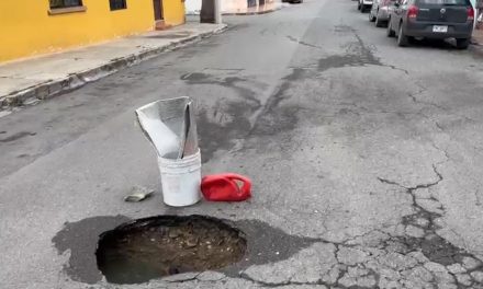 Alertan a automovilistas con botes por la presencia de un bache a media calle en Oceanía